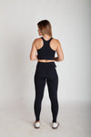 Legging fitness feminina preta e off white com bolsos laterais em Nagoya vista costas corpo inteiro