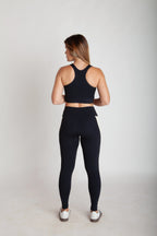 Legging fitness feminina preta e off white com bolsos laterais em Nagoya vista costas corpo inteiro